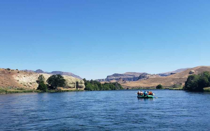 a raft is paddled by outward bound students on a calm river